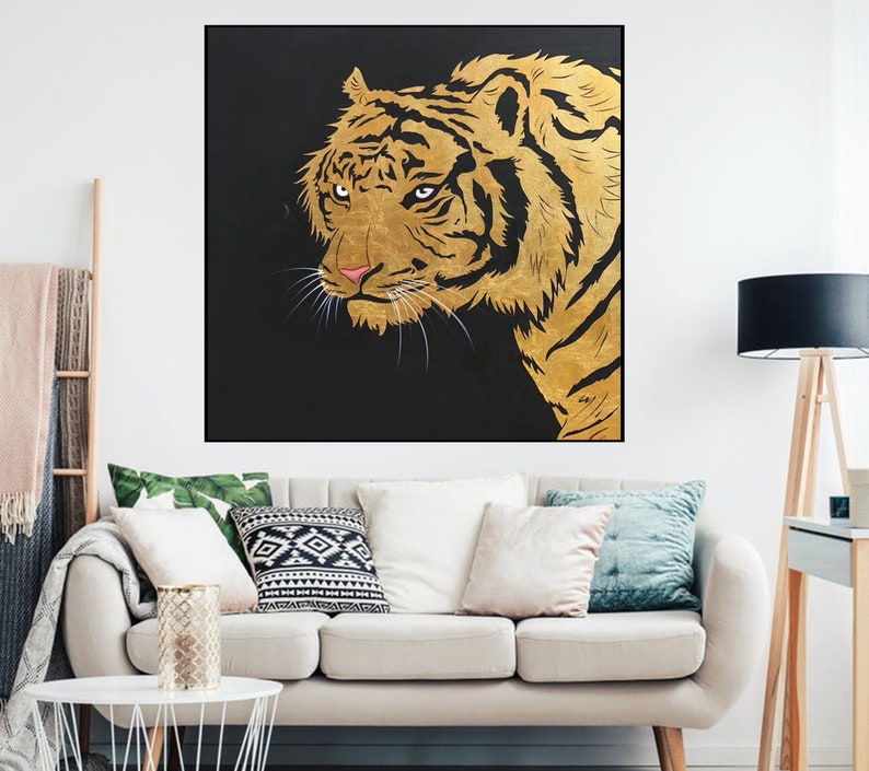 May include: A close-up of a golden tiger's face against a black background. The tiger's fur is detailed with gold paint and the eyes are a deep, dark brown.