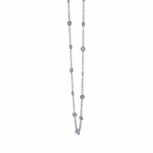 May include: A delicate silver necklace featuring multiple round, clear gemstones evenly spaced along the chain. The necklace is displayed against a plain white background, highlighting the sparkle of the gemstones.