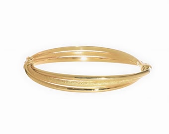 May include: A gold-colored bracelet with a three-strand design. The bracelet has a smooth, polished finish and a clasp closure. The jewelry is set against a white background.