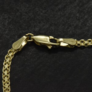 May include: Close-up of a gold chain necklace with a lobster clasp. The clasp is marked with the number "925".