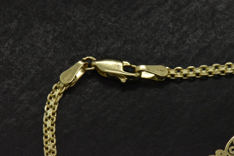 May include: Close-up of a gold chain necklace with a lobster clasp. The clasp is marked with the number "925".