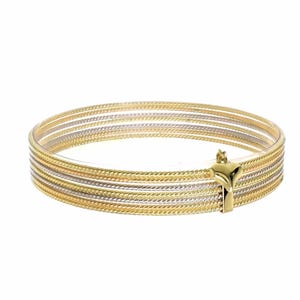 Può includere: Un braccialetto rigido in oro con più bande di diverse larghezze e trame. Il braccialetto è realizzato in oro giallo e bianco e ha una chiusura a forma di cuore.