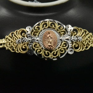 May include: A gold and silver filigree necklace with a round pendant featuring a religious figure. The pendant is made of rose gold and has a detailed design.