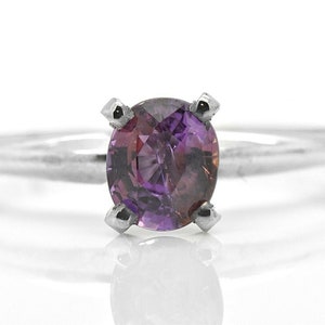 May include: A silver ring with a purple gemstone set in a four-prong setting.
