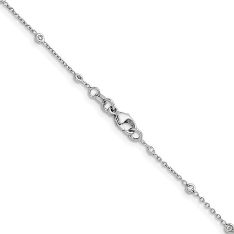 May include: A delicate silver necklace with small, round, clear gemstones evenly spaced along the chain. The necklace features a lobster clasp closure and is designed for a minimalist aesthetic. The chain is thin and appears to be made of a shiny metal.
