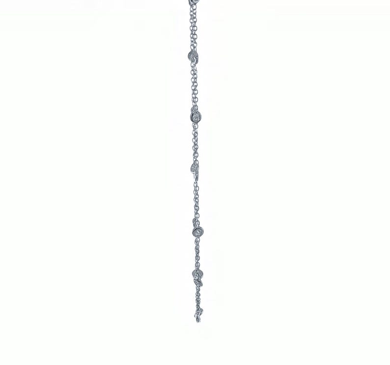 May include: A delicate silver necklace with multiple small, round, clear gemstones evenly spaced along the chain. The necklace is displayed against a white background, highlighting its simple elegance. The chain is approximately 18 inches long.