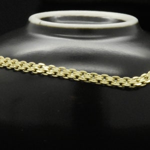 May include: A gold chain bracelet with a three-toned pendant. The pendant is a floral design with a center stone.