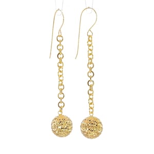 May include: A pair of gold dangle earrings with textured ball charms hanging from delicate chains.