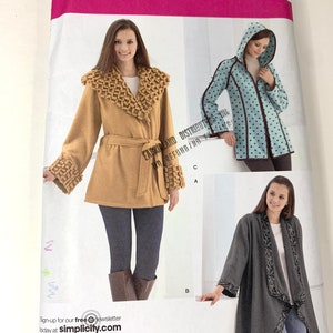 May include: A sewing pattern for three different jackets. The first jacket is a brown wrap jacket with a large collar and a belt. The second jacket is a blue hooded jacket with white polka dots. The third jacket is a grey wrap jacket with a black floral design. The pattern is for sizes XS, S, M, L, and XL. The pattern is from Simplicity.
