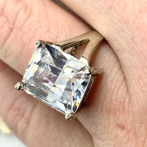 Peut inclure: Une bague en argent avec une grosse pierre en zircone cubique carrée et transparente.