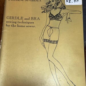 May include: A vintage book cover titled "Sew Lovely Lingerie" by Laverne Devereaux. The cover features a line drawing of a woman in lingerie, with text indicating sewing techniques for girdles and bras. The price tag shows £2.00.