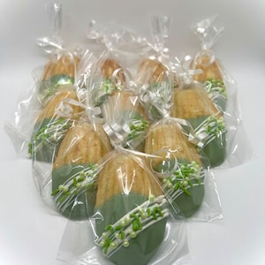 May include: A group of individually packaged green and white chocolate-covered madeleines with green and white sprinkles.