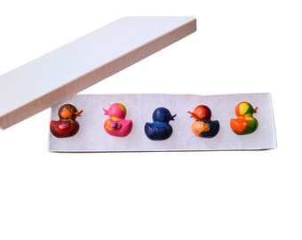 May include: A set of five colorful crayon ducks in a white box. The ducks are in shades of red, pink, blue, orange, and yellow.