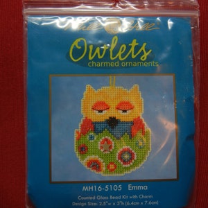 May include: A counted glass bead kit with charm to create an owl ornament. The owl is yellow with blue, green, and red accents. The kit is called "Owlets charmed ornaments" and the design is called "Emma". The design size is 2.5 inches wide by 3 inches high (6.4 cm x 7.6 cm).
