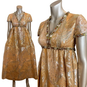 May include: A gold brocade maxi dress with a V-neckline and short sleeves. The dress is embellished with a beaded trim around the neckline and waist.