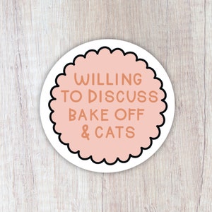 May include: A pink and white round sticker with a scalloped edge. The sticker says "Willing to Discuss Bake Off & Cats" in brown text.