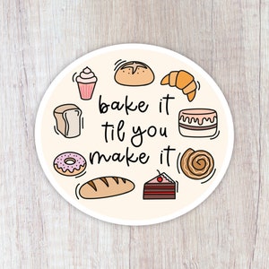 May include: A round sticker with a light beige background and a white border. The sticker features a variety of baked goods, including a donut, a croissant, a cupcake, a loaf of bread, a cinnamon roll, a cake, and a chocolate cake. The text "bake it til you make it" is written in black cursive font.