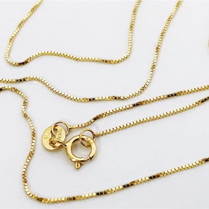 May include: A gold chain necklace with a box chain style. The chain has a lobster clasp and a tag that reads "10K" and "13".