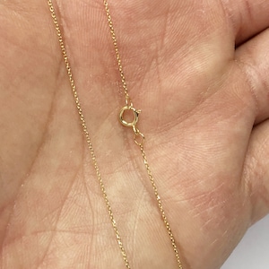 K&ouml;nnte beinhalten: Eine goldene Kettenkette mit einem Karabinerverschluss.
