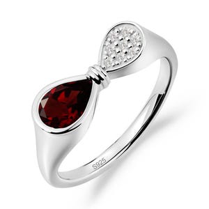 Peut inclure: Une bague en argent sterling avec une pierre grenat rouge foncé en forme de poire d'un côté et une section plus petite en forme de poire incrustée de minuscules pierres blanches claires de l'autre, reliées par un détail nervuré. S925 gravé.