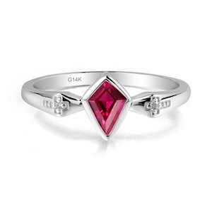 May include: A silver ring featuring a diamond-shaped, deep red gemstone. The ring has a polished band and small, cross-shaped accents with tiny stones on either side of the central gem. The inscription "G14K" is visible on the band.