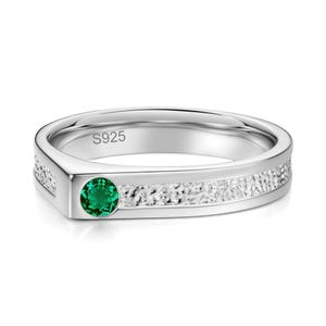 Op de afbeelding: Een zilverkleurige ring met een getextureerde band en een enkele rondgeslepen groene edelsteen aan de voorzijde. De binnenzijde van de ring is duidelijk gegraveerd met de tekst S925, wat de metaalsamenstelling van dit sieraad aangeeft.