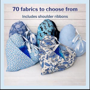 Peut inclure: Sacs en tissu en forme de c&oelig;ur avec diff&eacute;rents motifs bleus, dont des motifs floraux, cachemire et &agrave; pois, avec des poign&eacute;es en ruban blanc. Les sacs ont des poches et le texte "70 fabrics to choose from" et "Includes shoulder ribbons".