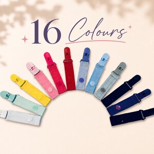 May include: A collection of sixteen colorful fabric clips, each with a plastic clasp. The clips are arranged in a semi-circle, showcasing a variety of colors including pink, red, blue, and yellow. The text "16 Colours" is displayed above the clips.