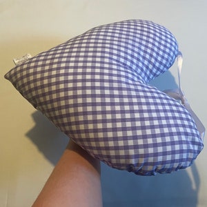 Op de afbeelding: Een hartvormig kussen met een paars-wit geruit patroon. Het kussen heeft een wit lint eromheen gebonden.