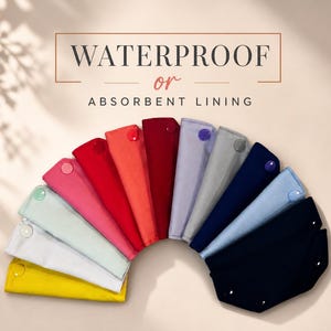 May include: A fan of folded fabric items in a range of colours, including yellow, white, light green, pink, red, and navy blue. Each item has a snap closure. The text "WATERPROOF or ABSORBENT LINING" is displayed above. The items are arranged in a semi-circle.