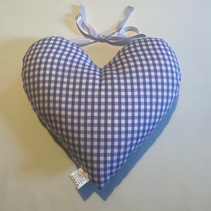 Op de afbeelding: Een hartvormig kussen van paars en wit gingham met een wit satijnen lint dat bovenaan is gebonden.