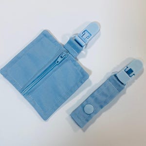 Könnte beinhalten: Zwei hellblaue Stoff-Reißverschlusstaschen mit Plastikclips. Eine Tasche hat einen Reißverschluss und die andere einen Knopfverschluss.