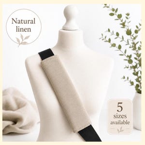 May include: A beige natural linen strap cover positioned on a black strap over a mannequin torso. The image includes text that reads Natural linen and 5 sizes available. The cover is rectangular with stitched edges and a neutral light tan color.