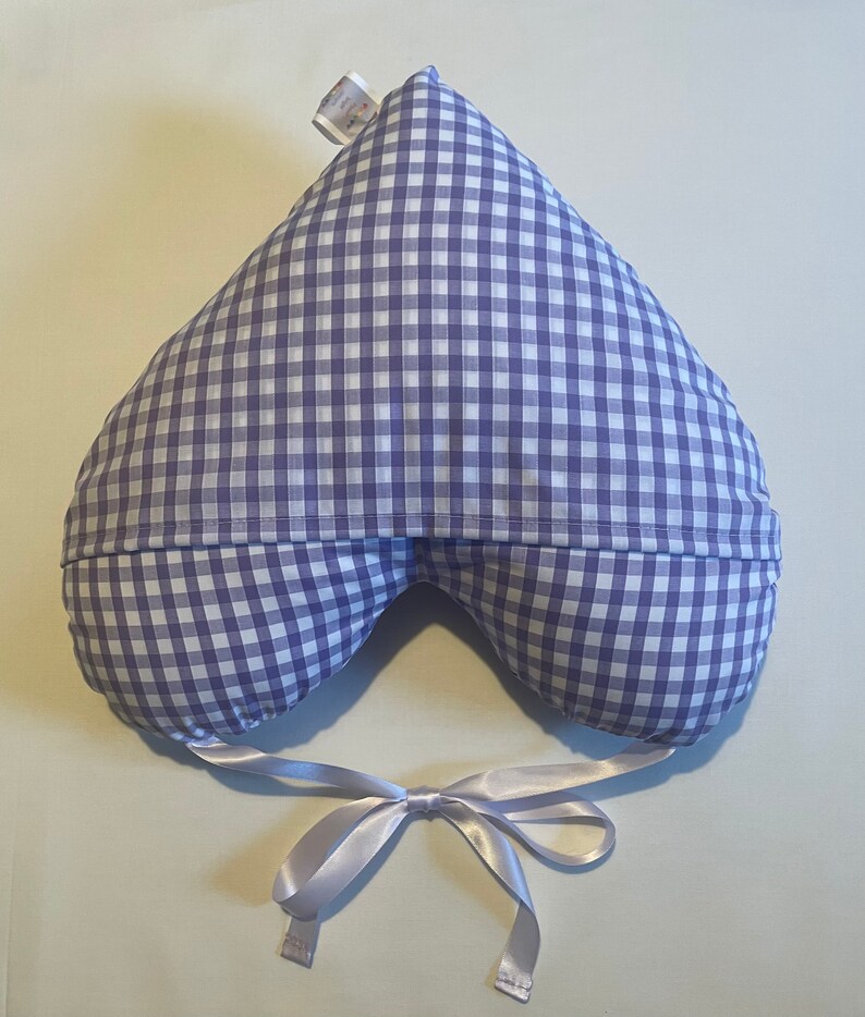 Op de afbeelding: Een hartvormig voedingskussen met een blauw-wit geruit patroon. Het kussen heeft een wit satijnen lint eromheen gebonden.
