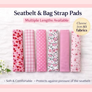 May include: Six seatbelt and bag strap pads with different pink patterns, including hearts, gingham, polka dots, and floral designs. The text reads "Seatbelt & Bag Strap Pads" and "Choose from 83 fabrics". The pads are described as soft and comfortable.