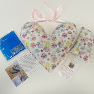 May include: A heart-shaped pillow with a floral and gnome print, a smaller rectangular pillow with the same print, a blue ice pack, and a card with instructions on how to use a mastectomy pillow. The card also includes the text "Pastel Bright Designs" and a website address.