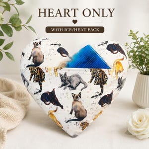 May include: A heart-shaped fabric pillow featuring a pattern of various cats in different poses. The pillow has a pocket containing a blue gel ice or heat pack. Text above the pillow reads HEART ONLY WITH ICE/HEAT PACK in dark brown letters.