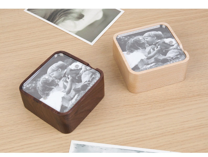 May include: Two wooden photo boxes with a square shape. One box is light brown and the other is dark brown. Both boxes have a clear glass insert that displays a black and white photo of two children.