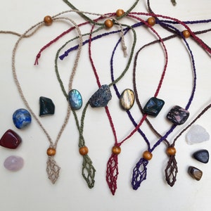 May include: Seven handmade macrame necklaces with various colored cords and gemstone pendants. The pendants include a blue lapis lazuli, a green aventurine, a blue labradorite, a brown tiger's eye, a green aventurine, a pink rhodochrosite, and a clear quartz.