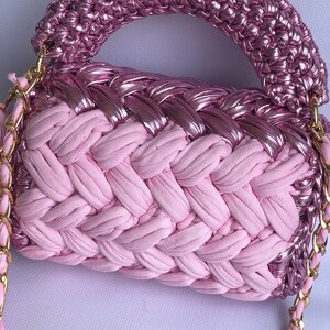 May include: A pink woven handbag with a metallic pink top and a gold chain strap.