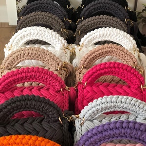 Peut inclure: Une collection de sacs &agrave; main en crochet de diff&eacute;rentes couleurs, notamment noir, marron, blanc, beige, rose, violet, orange et gris. Les sacs &agrave; main ont un design tress&eacute; unique et des cha&icirc;nes dor&eacute;es.
