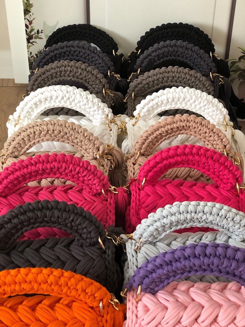 Peut inclure: Une collection de sacs &agrave; main en crochet de diff&eacute;rentes couleurs, notamment noir, marron, blanc, beige, rose, violet, orange et gris. Les sacs &agrave; main ont un design tress&eacute; unique et des cha&icirc;nes dor&eacute;es.