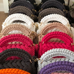 Peut inclure: Une collection de sacs &agrave; main en crochet de diff&eacute;rentes couleurs, notamment noir, marron, blanc, beige, rose, rouge, gris, violet, orange et rose clair. Les sacs &agrave; main ont un design tiss&eacute; unique et des poign&eacute;es en cha&icirc;ne dor&eacute;es.