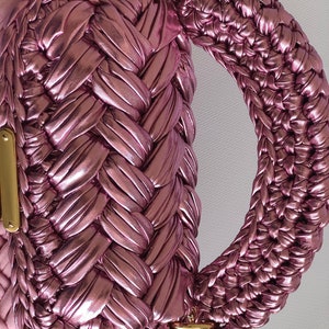 May include: A pink woven handbag with a braided handle and gold hardware.