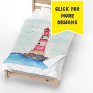May include: A blanket with a watercolour design of a red and white striped lighthouse on a rocky shore, with blue water and seagulls. The blanket is on a bed. The image includes the text "CLICK FOR MORE DESIGNS".