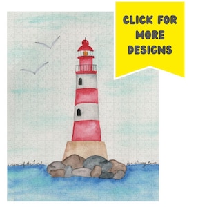 May include: A watercolour puzzle depicting a red and white striped lighthouse on a rocky base, set against a blue sea and sky. Two seagulls fly above. The text "CLICK FOR MORE DESIGNS" is in a yellow banner.