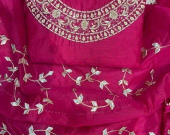 May include: A vibrant fuchsia-colored garment with intricate gold embroidery around the neckline. The fabric has a delicate, sheer quality, with silver leaf-shaped embellishments scattered across the surface. The design suggests traditional wear.