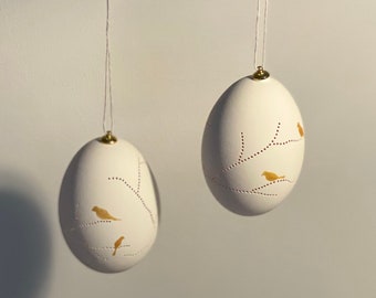 two hand carved goose eggs painted with golden birds