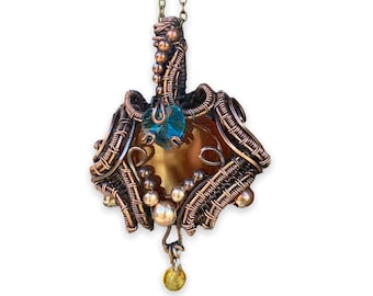 May include: A copper wire wrapped pendant with a brown and blue gemstone. The pendant is attached to a gold chain.