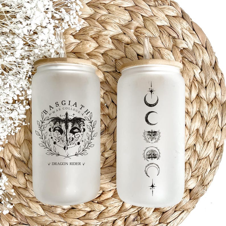May include: Two frosted glass tumblers with bamboo lids and reusable glass straws. One tumbler features a black and white illustration of a dragon with the text "Basgiath War College *Dragon Rider*" and the other tumbler features a black and white illustration of a crescent moon, stars, and a wolf's head.